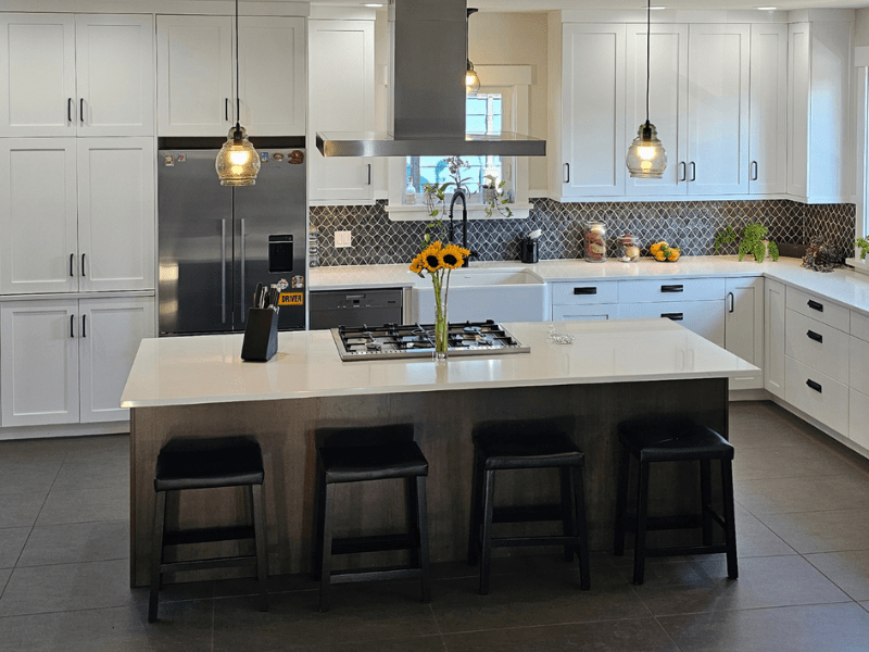 White shaker kitchen with large island, stainless hood, and mosaic backsplash