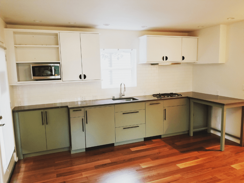 Sage green kitchen with white uppers and hardwood floors