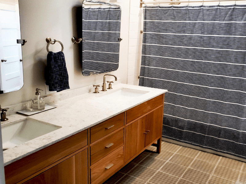 Double vanity bathroom with marble counters and warm wood cabinetry