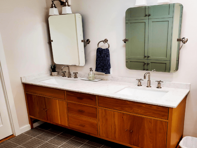 Bathroom with double wood vanity, marble top, and pivot mirrors